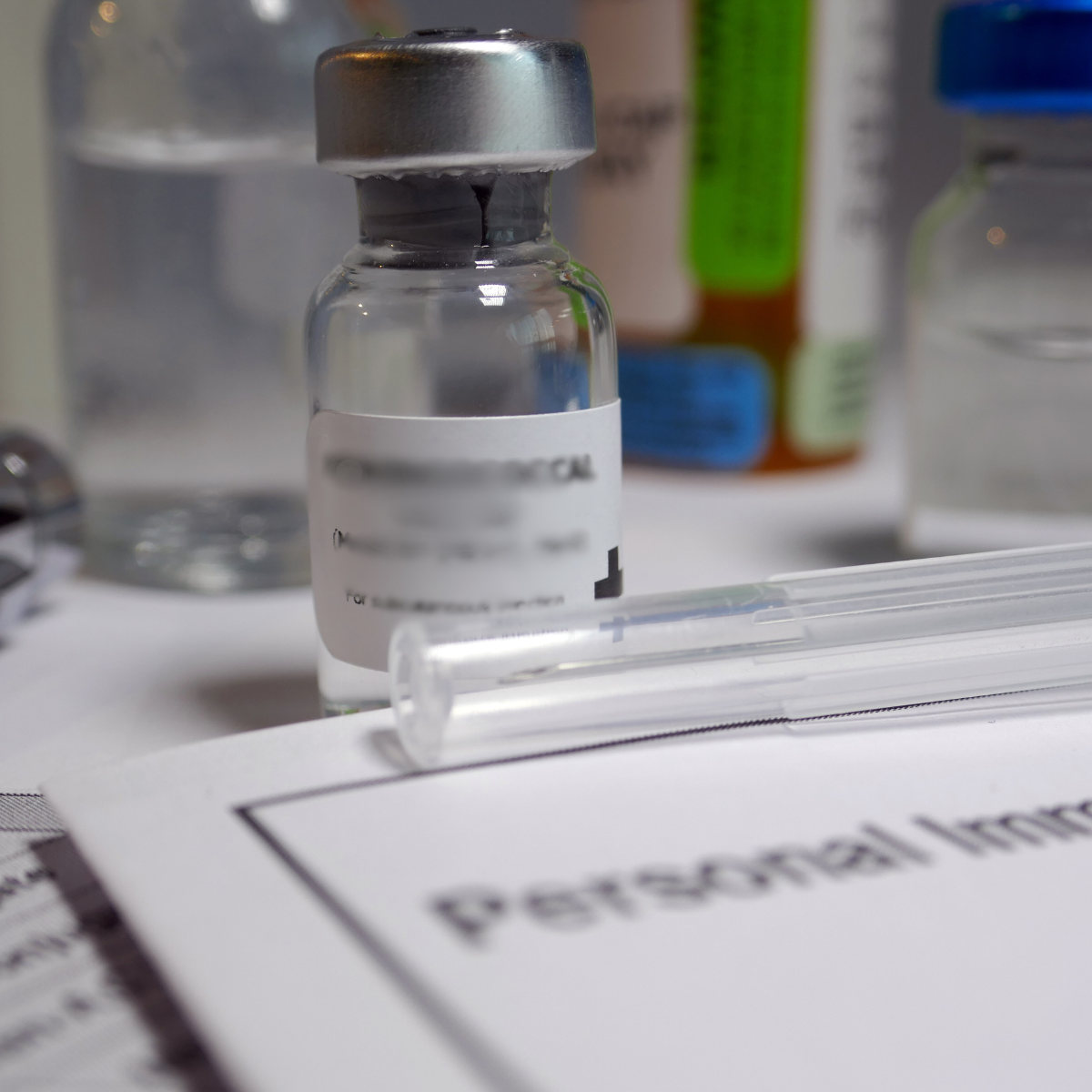 Prancheta com formulários médicos sob mesa e um vidrinho de medicação líquida na parte superior